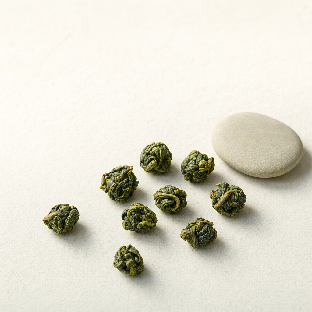 A small relaxed scatter of rolled Cloud Ridge Oolong pellets on a pale stone surface