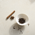 Yunnan Crown Reserve Pu-erh loose dark reddish-brown leaf in a small white porcelain bowl on a bright stone surface, with a star-anise accent