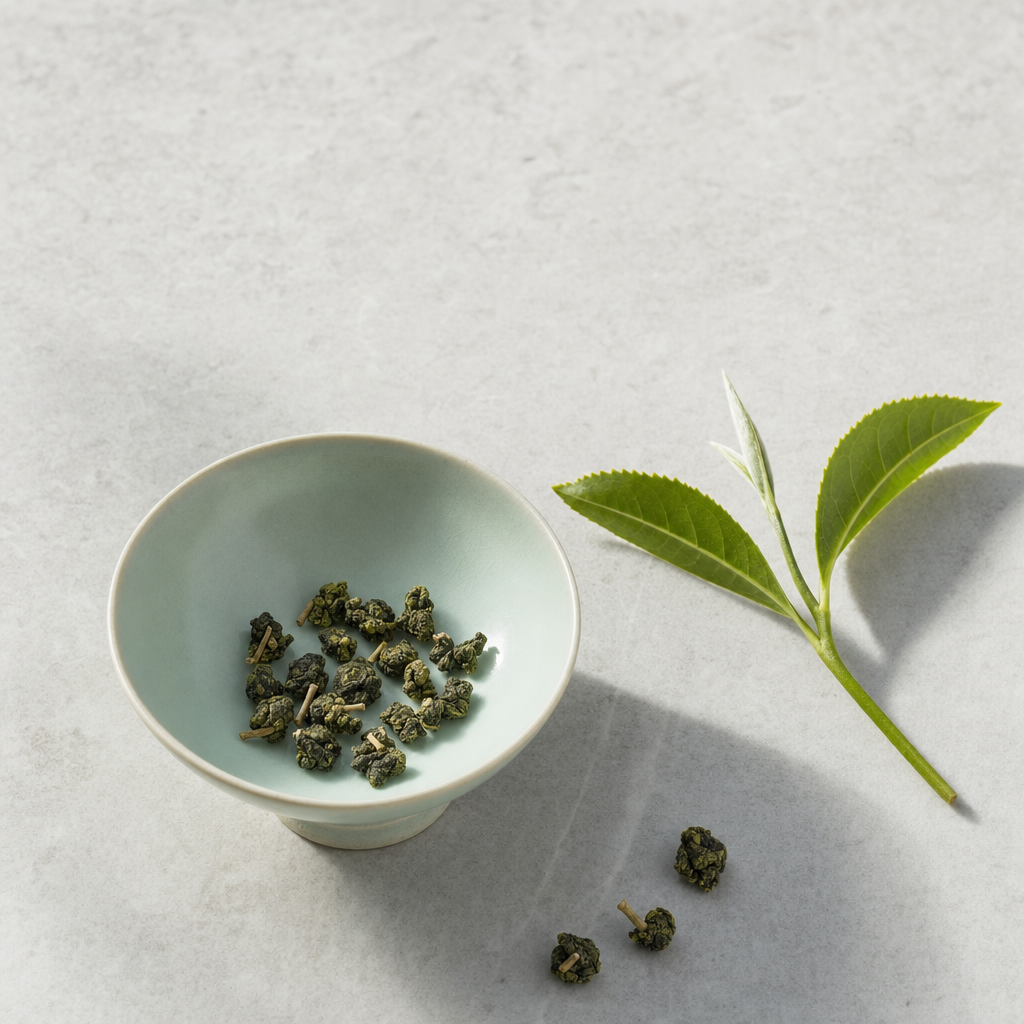 Mountain Crown Signature Oolong loose-leaf rolled jade pellets in a pale celadon bowl on a bright stone surface, with a fresh one-bud-two-leaves tea sprig